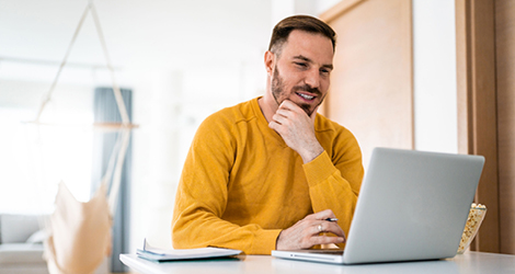 Man in yellow shirt on laptop